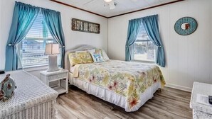 Ein Schlafzimmer mit einem Bett, einem Nachttisch, einer Lampe und einem Deckenventilator.