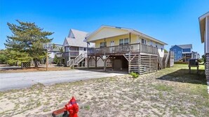 Ein Strandhaus mit Balkon und einem roten Hydranten im Vordergrund.