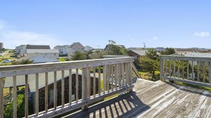 Une terrasse en bois offrant une vue sur des maisons et un ciel dégagé.