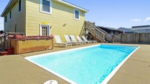 Une maison à deux étages avec une piscine, un jacuzzi et une terrasse en bois.