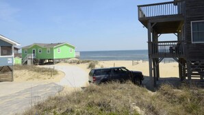 A beach house with a wooden deck and a view of the ocean.