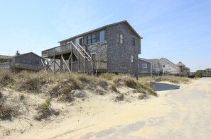Situated on sandy terrain, this traditional building features a prominent staircase leading to an upper level.
