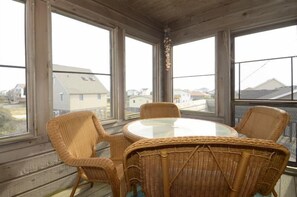 Relax in a traditional room with a large round table and four chairs, surrounded by high ceilings and large windows offering views of the neighborhood.