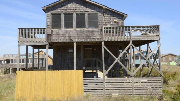 A wooden house with a balcony and a covered porch.