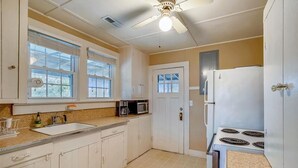 A kitchen with white cabinets, a microwave, a stove, and a ceiling fan. - Old Nags Head style with wrap around porch! Soundside Rd in Nags Head! (Nags Head)