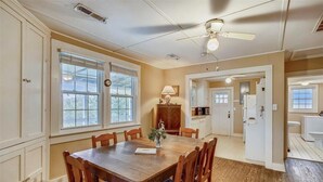 A dining room with a wooden table and chairs, a ceiling fan, and a view into the kitchen. - Old Nags Head style with wrap around porch! Soundside Rd in Nags Head! (Nags Head)