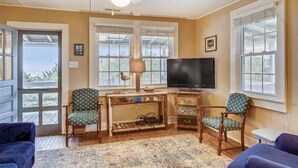 A cozy living room with a ceiling fan, a television, and two chairs. - Old Nags Head style with wrap around porch! Soundside Rd in Nags Head! (Nags Head)