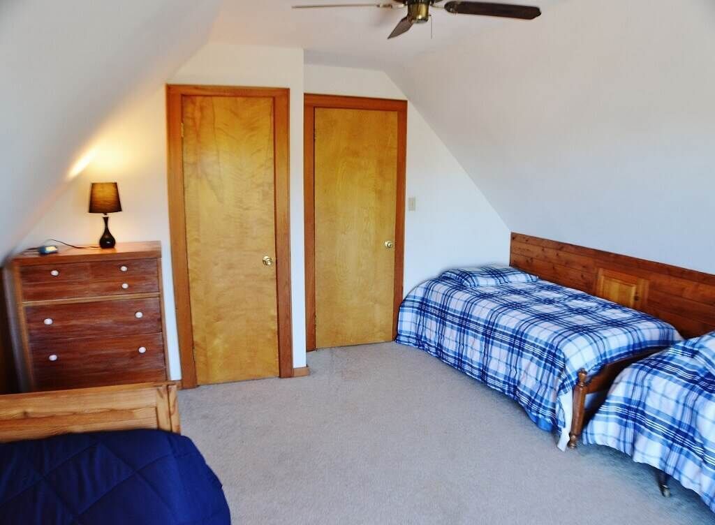 A bedroom with two beds, a dresser, and two doors.