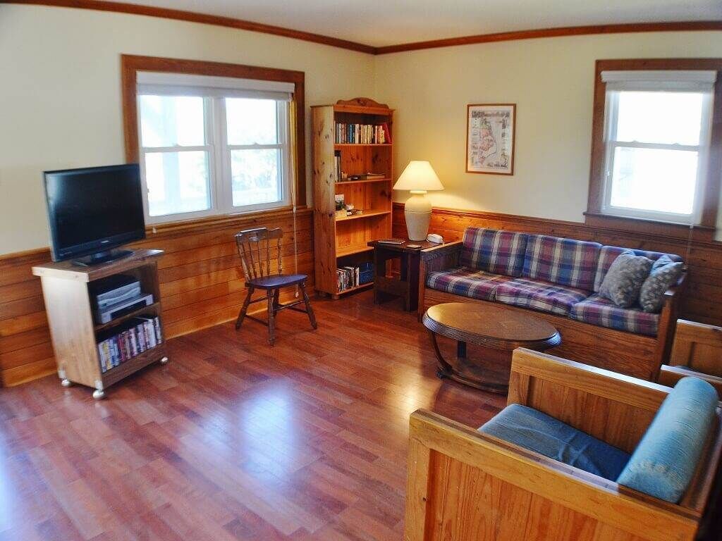 A living room with a television, bookshelves, a sofa, and a lamp.