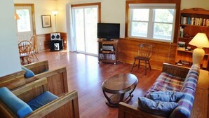 Amplia sala de estar con piso de madera, televisor, estantería y chimenea.