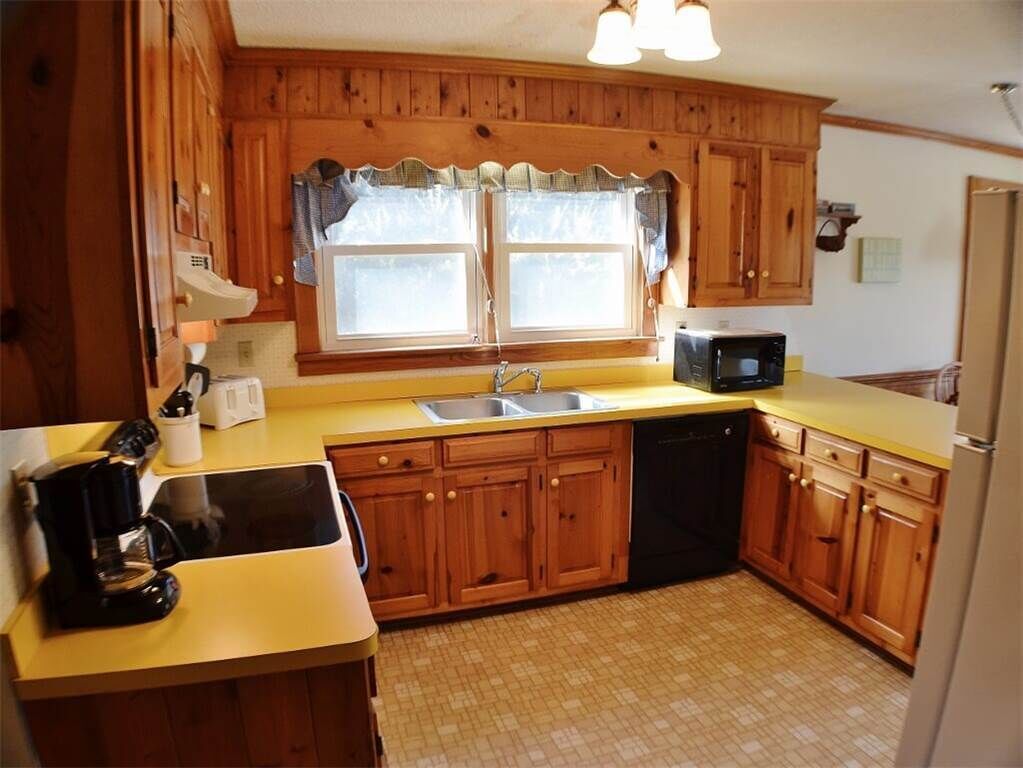 A kitchen with wooden cabinets, a microwave, a coffee maker, and a dishwasher.