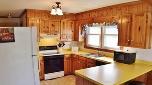Una cocina con armarios de madera, un refrigerador, una estufa, un microondas y una encimera amarilla.