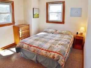 A bedroom with a bed, dresser, nightstand, and two windows. - Just blocks from the beach on a budget! Nostalgic 3 BR cottage in Nags Head! (Nags Head)