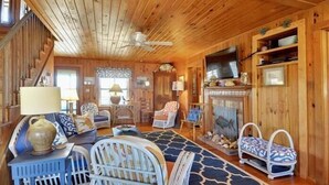 A wooden interior with a sofa, chairs, a television, and a fireplace. - Classic Outer Banks style oceanfront home in Kill Devil Hills! (Kill Devil Hills)