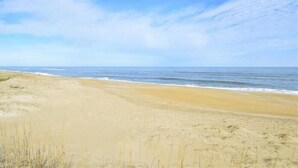 A beach with a clear sky and calm sea. - Classic Outer Banks style oceanfront home in Kill Devil Hills! (Kill Devil Hills)