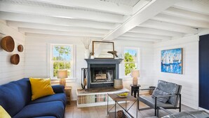 Ein Wohnzimmer mit Kamin, einem blauen Sofa, einem grauen Sessel und einem Gemälde an der Wand.