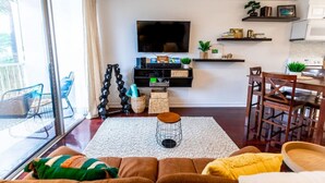 Een moderne woonkamer met een grote televisie, een eethoek en een keuken.
