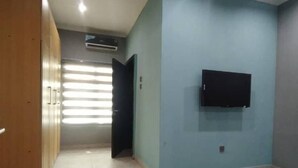 A room with a TV mounted on the wall, a wardrobe, and a door leading to another room. - lovely 4bedroom in a well-secured estate (Lagos)