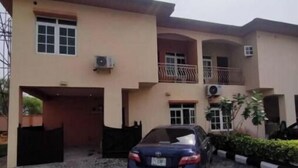 A two-story building with a car parked in the driveway. - lovely 4bedroom in a well-secured estate (Lagos)