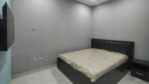 A bedroom with a bed, a nightstand, and a wall-mounted TV. - lovely 4bedroom in a well-secured estate (Lagos)