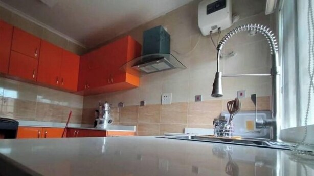 A kitchen with a large island, orange cabinets, and a stainless steel range hood. - lovely 4bedroom in a well-secured estate (Lagos)