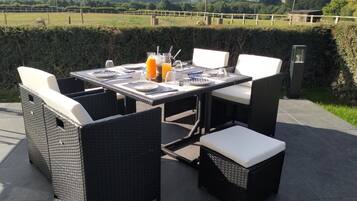 Enjoy al fresco dining with a table set for four, surrounded by comfortable wicker chairs and a beautiful view.