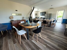 Cocina moderna con comedor, que incluye una mesa de madera, sillas y vistas al exterior.
