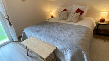 Une chambre à coucher avec un lit, des oreillers, des lampes de chevet, un banc en bois et un élément décoratif mural.