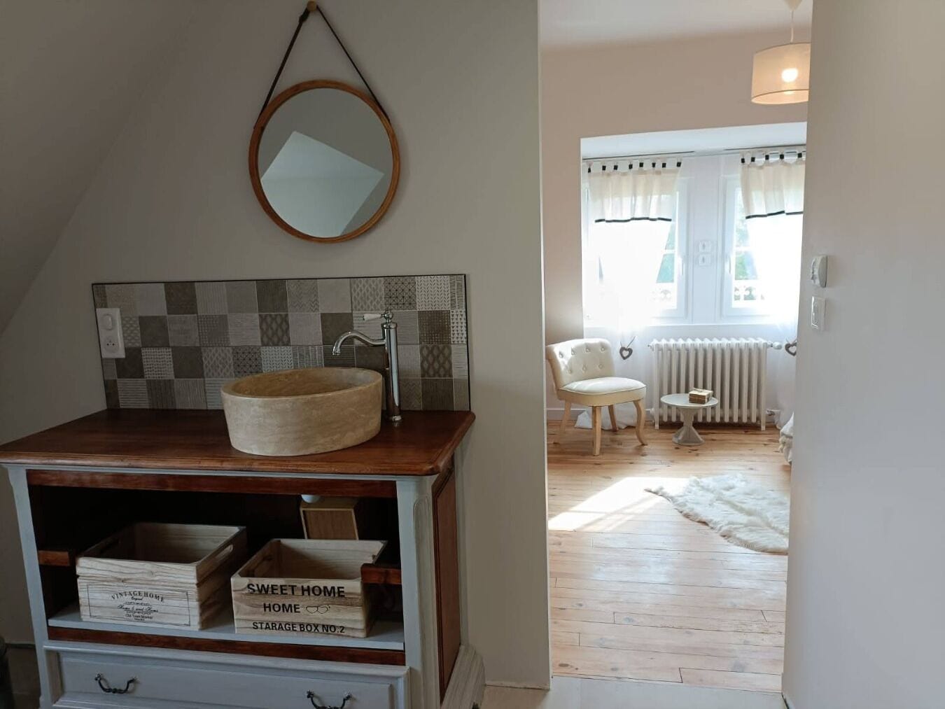 Une salle de bain avec un meuble-lavabo en bois, un miroir rond et un pare-feu en carreaux.