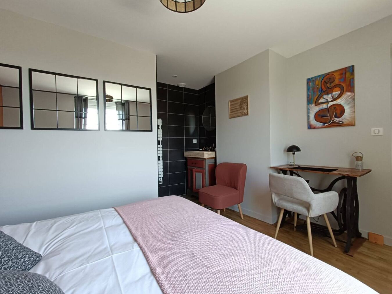 A bedroom with a bed, a desk, a chair, and a small kitchenette.