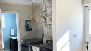 A laundry room with two washing machines, a drying rack, and a chandelier.