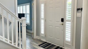 A hallway with a white door, a staircase, and a window with blinds. - Guest-Favorite Rehoboth Beach Retreat:10/10 Reviews - Book early! (Rehoboth Beach)