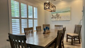 A dining room with a wooden table and chairs, a hanging light fixture, and a painting on the wall. - Guest-Favorite Rehoboth Beach Retreat:10/10 Reviews - Book early! (Rehoboth Beach)