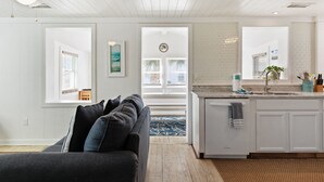 Una cocina moderna con armarios blancos, una isla integrada y un ventanal con persianas.