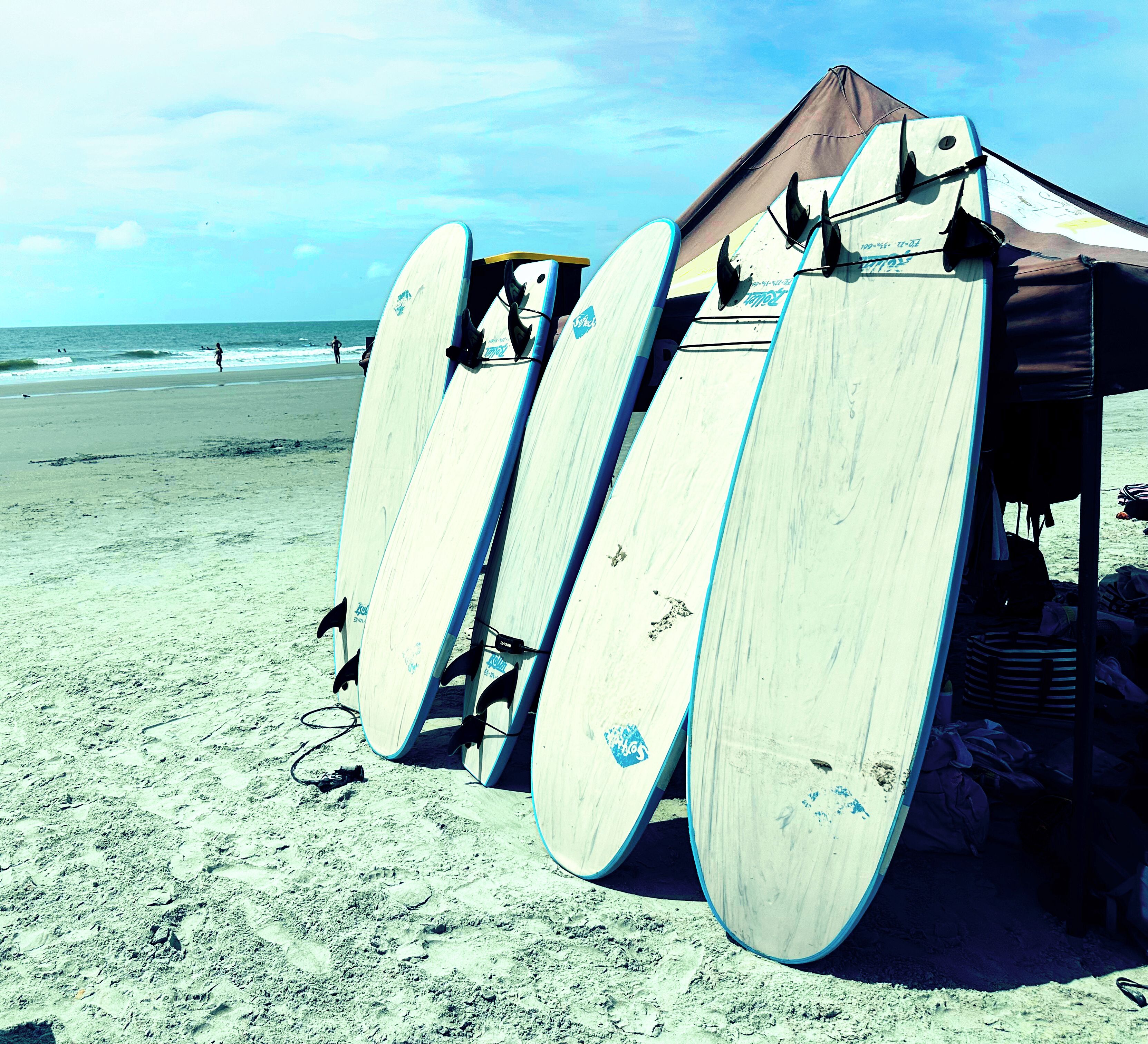 A beach with several surfboards leaning against a structure.