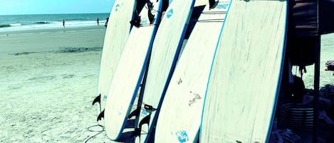 A beach with several surfboards leaning against a structure.