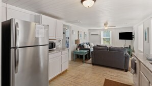 Una cocina moderna con refrigerador de acero inoxidable, armarios blancos y una mesa de centro verde azulado.