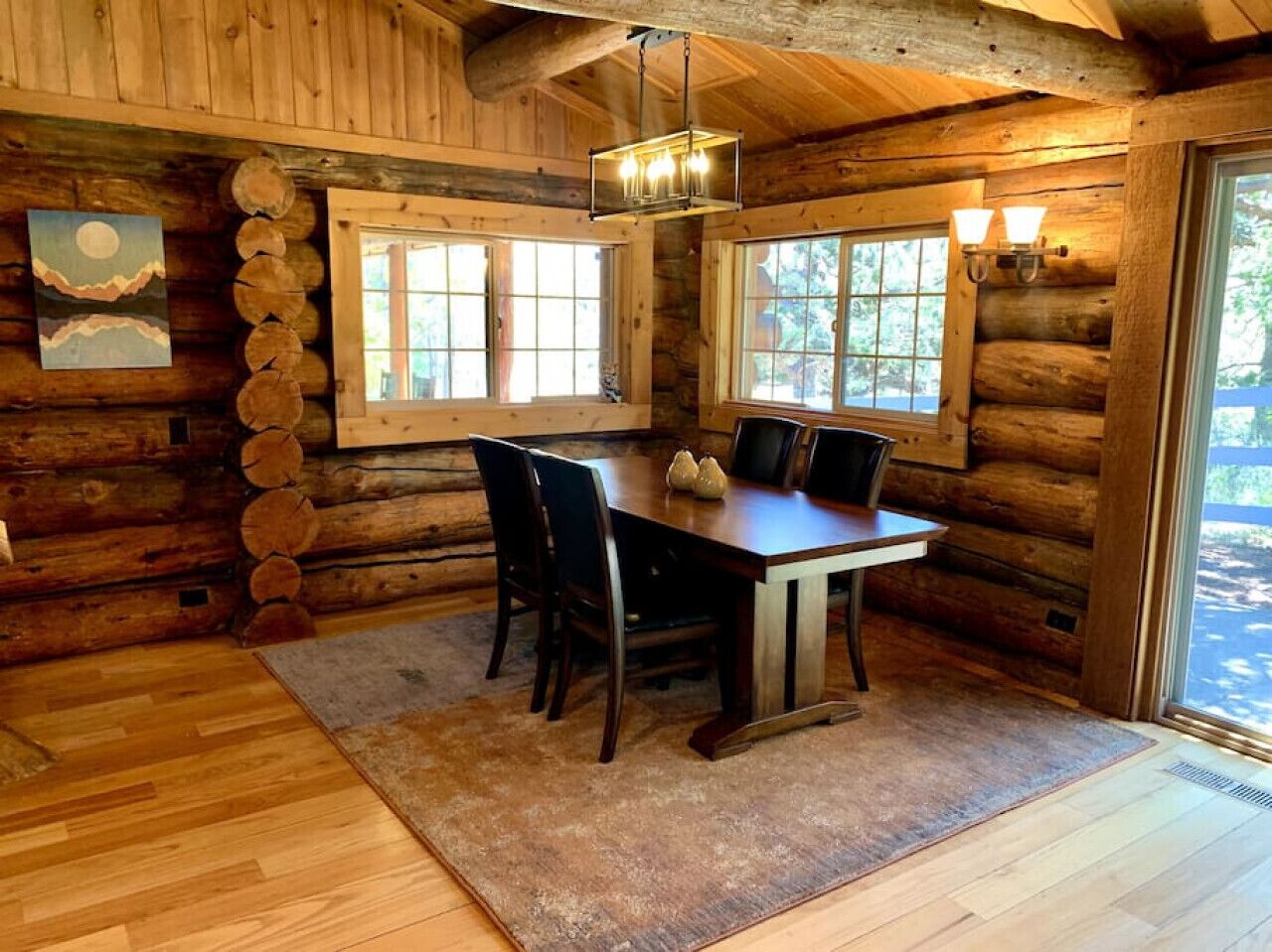 Een houten cabinemeubilair met een eettafel, stoelen en een kroonluchter.