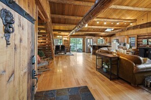 Un interior espacioso de cabaña de madera con piso de madera, sofá de cuero, comedor y cocina.