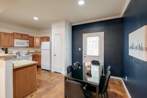A modern kitchen with wooden cabinets, a white refrigerator, and a dining area with a glass table and chairs. - SP3  Newly Reno Home 30% OFF! Mins to Medical Center (San Antonio)