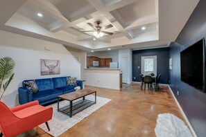 A spacious living area with a blue sofa, a red chair, a wooden coffee table, and a ceiling fan. - SP3  Newly Reno Home 30% OFF! Mins to Medical Center (San Antonio)