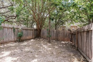 A fenced backyard with a dirt ground, a wooden fence, and a tree. - SP3  Newly Reno Home 30% OFF! Mins to Medical Center (San Antonio)