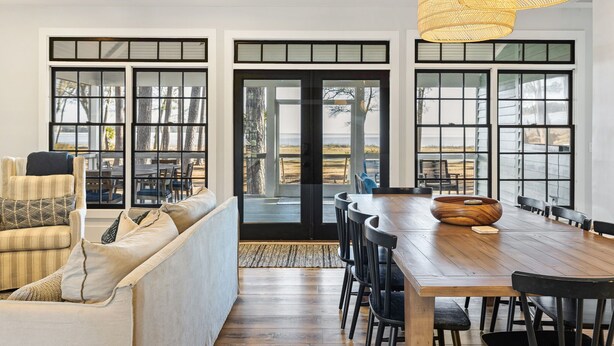 Un comedor moderno con una mesa de madera, sillas negras y una lámpara de fibra.