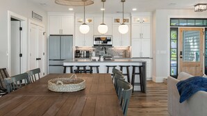 Una cocina moderna con armarios blancos, una isla central e iluminación colgante.