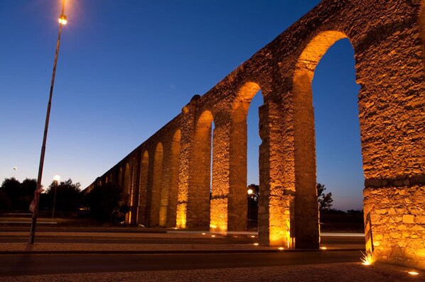 A stone aqueduct at dusk with warm lighting. - Almoura Ladeira (Évora)