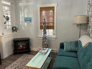 Un salon chaleureux avec une cheminée, un sapin de Noël et un canapé de couleur turquoise.