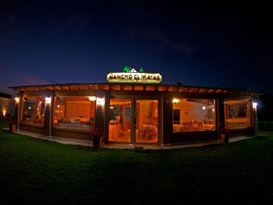 En godt oplyst toetages bygning med et skilt, der står 'Rancho El Mayab'.