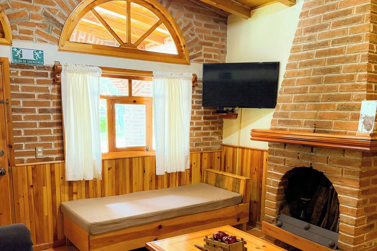 Una habitación acogedora con un banco de madera, un televisor en la pared y una chimenea.