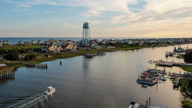 A river with boats, a water tower, and houses along the banks. - Salty Snouts Retreat, Pet Friendly Home With Fire Pit in Holden Beach, NC (Holden Beach)