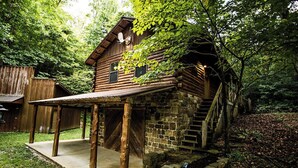 A rustic log cabin with a covered porch and a stone staircase leading to the entrance. - Bear Hollow near the Buffalo River  (Jasper)
